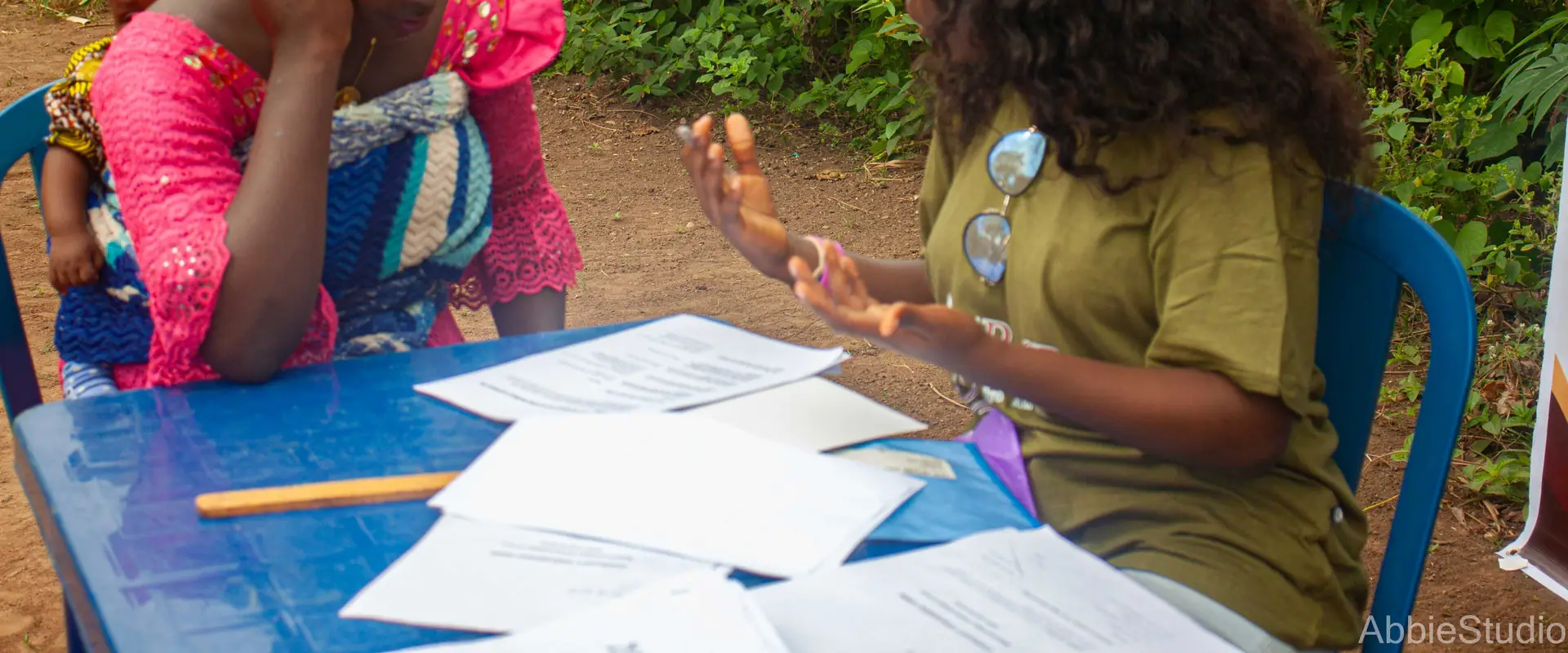 A volunteer at the registration table with a mother seated opposite, papers between them.