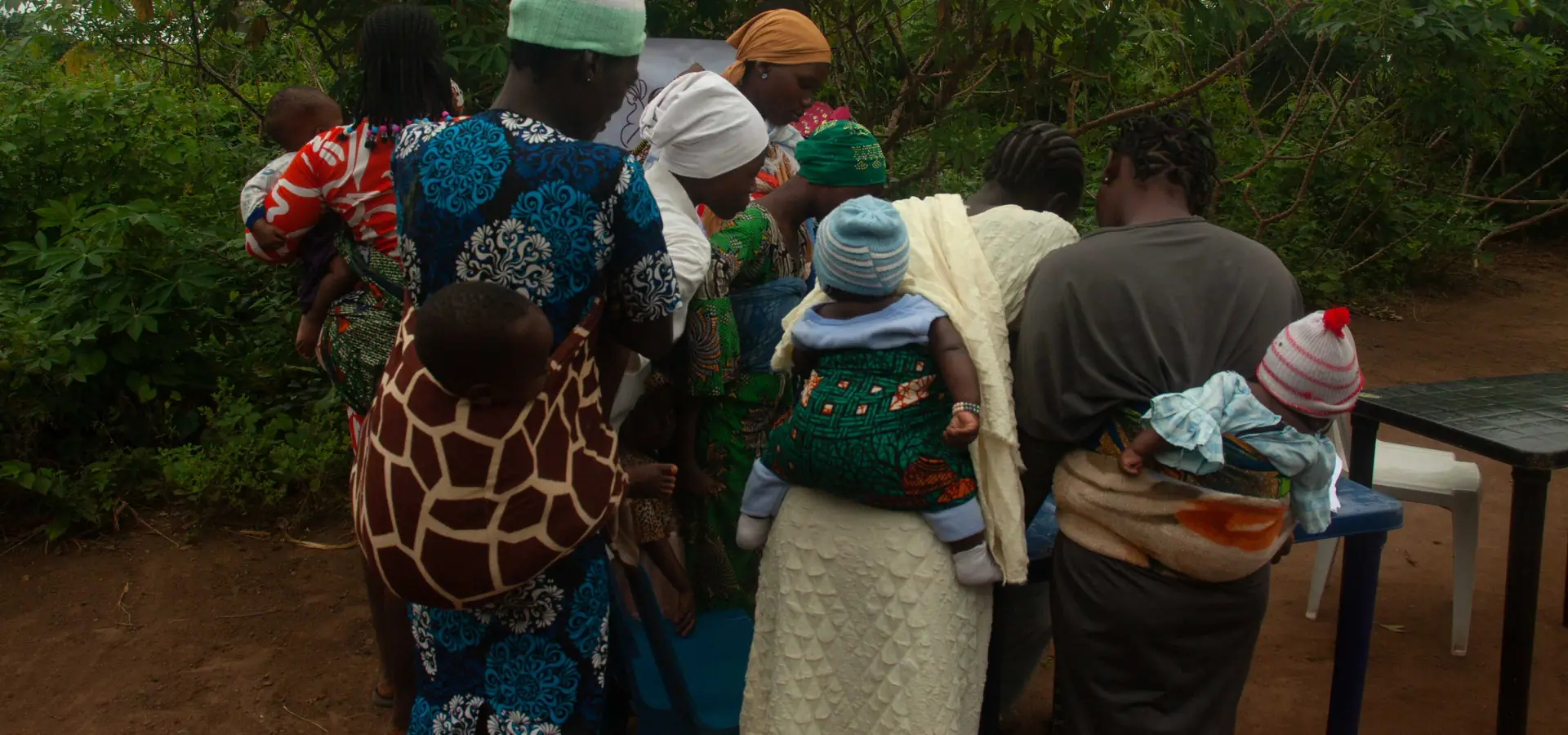 Mothers with infants carried on their backs, waiting together at the Ikogbo outreach.