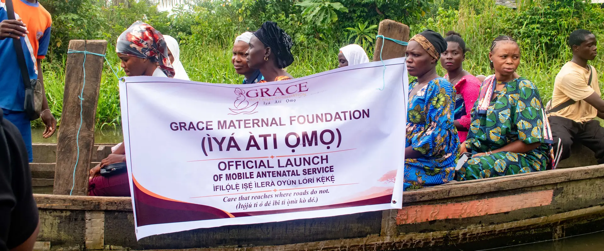 The launch banner held up in a boat on the water, with women seated behind it.