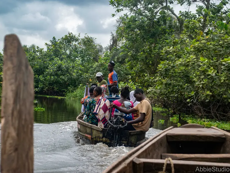 A boat setting out from the riverbank along a tree-lined waterway.