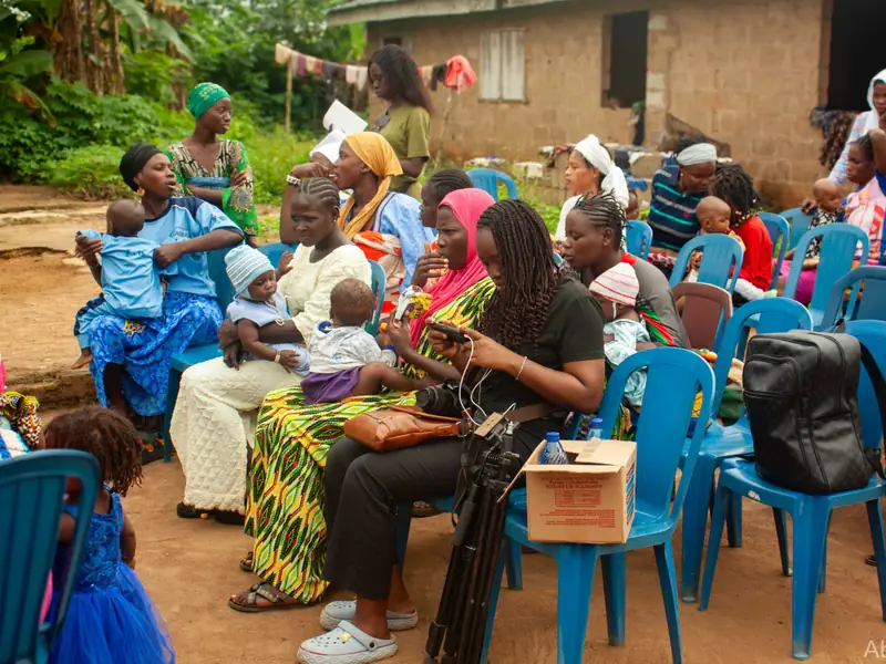 Women with their infants seated together outside a building.