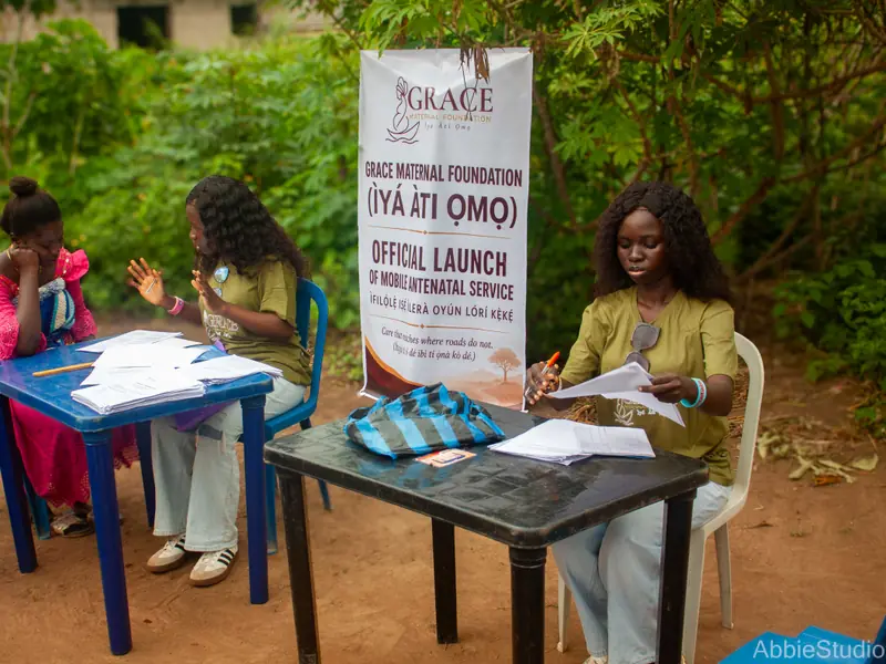 A registration table with the launch banner beside it and volunteers writing.