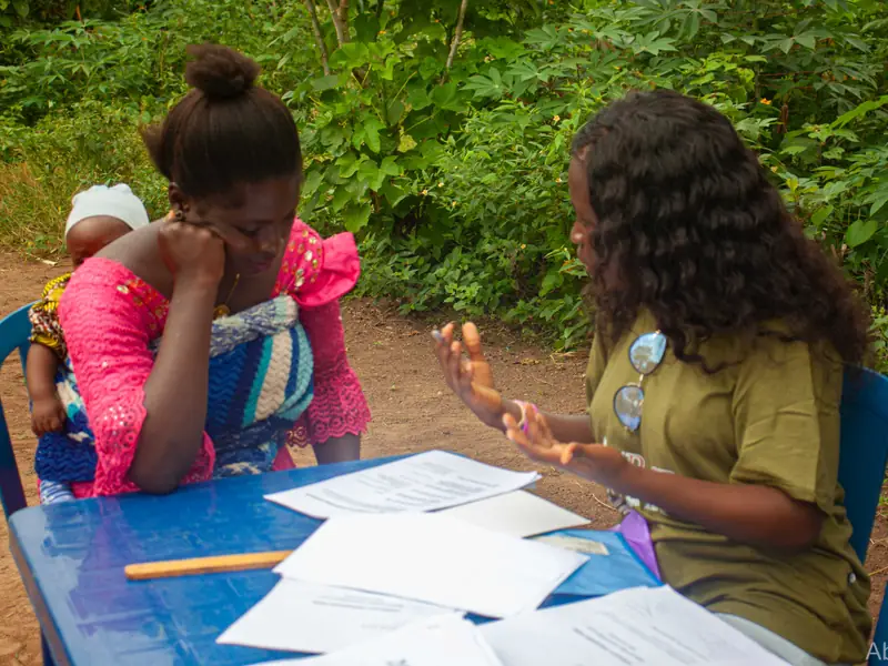 A volunteer at the table with a mother seated opposite.