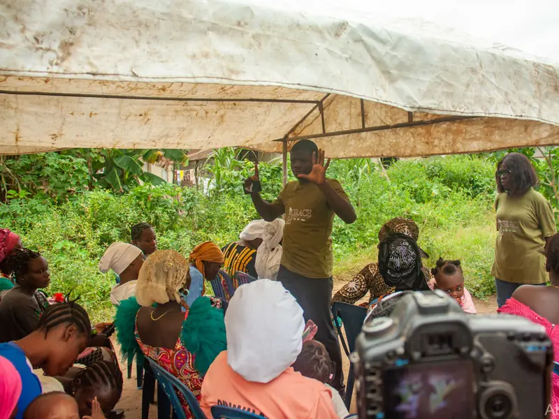 The health session under a tent, a speaker standing before seated women.