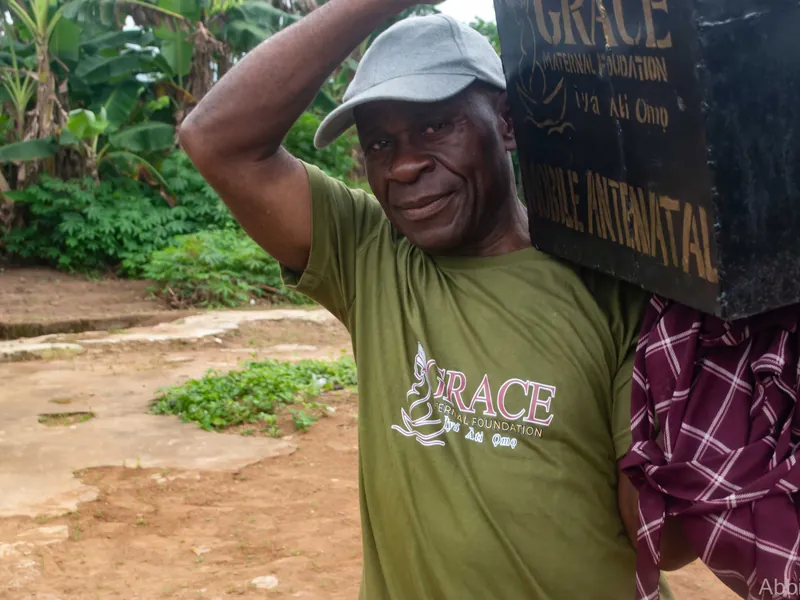 A volunteer in a Foundation T-shirt carrying the mobile antenatal box on his shoulder.
