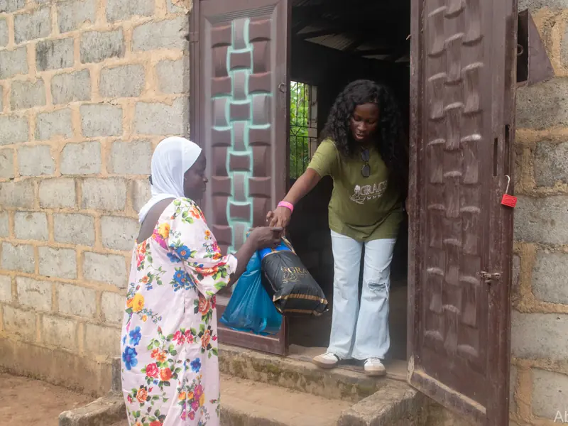 A volunteer handing a pack to a woman at a doorway.