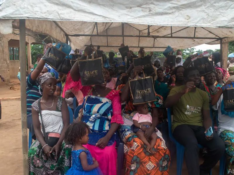 Women under the tent holding up the packs they received.
