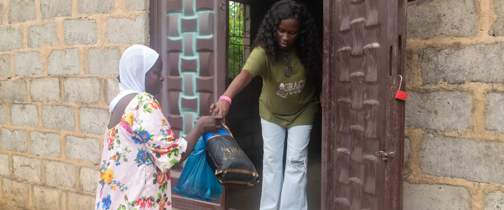 A volunteer handing a pack to a woman at a doorway.