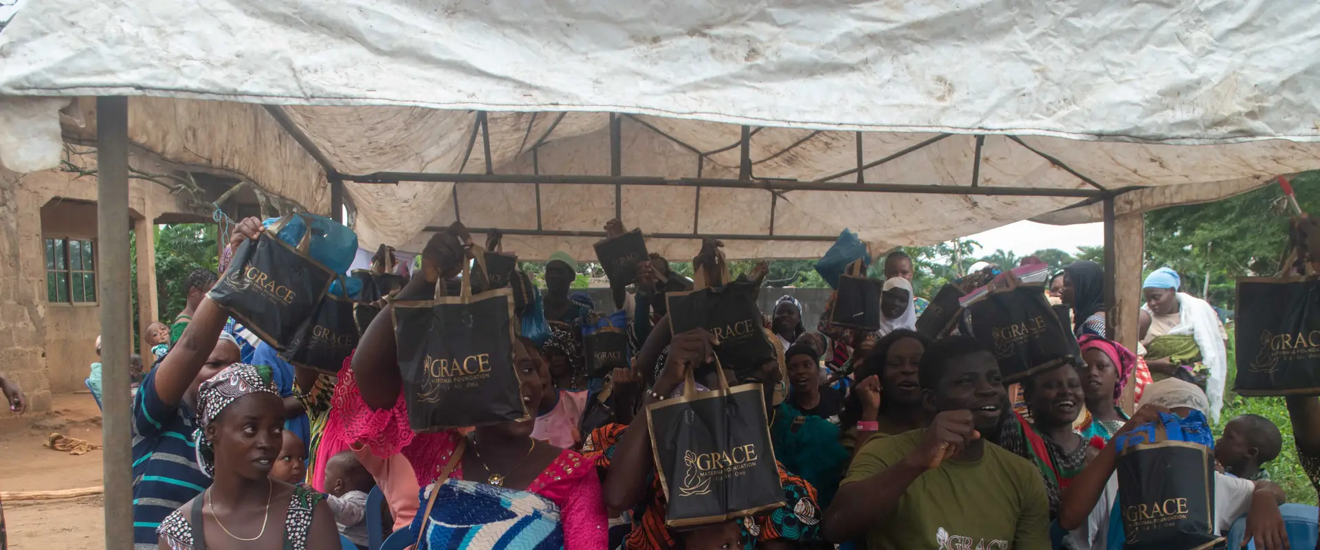 Women under the tent holding up the packs they received.